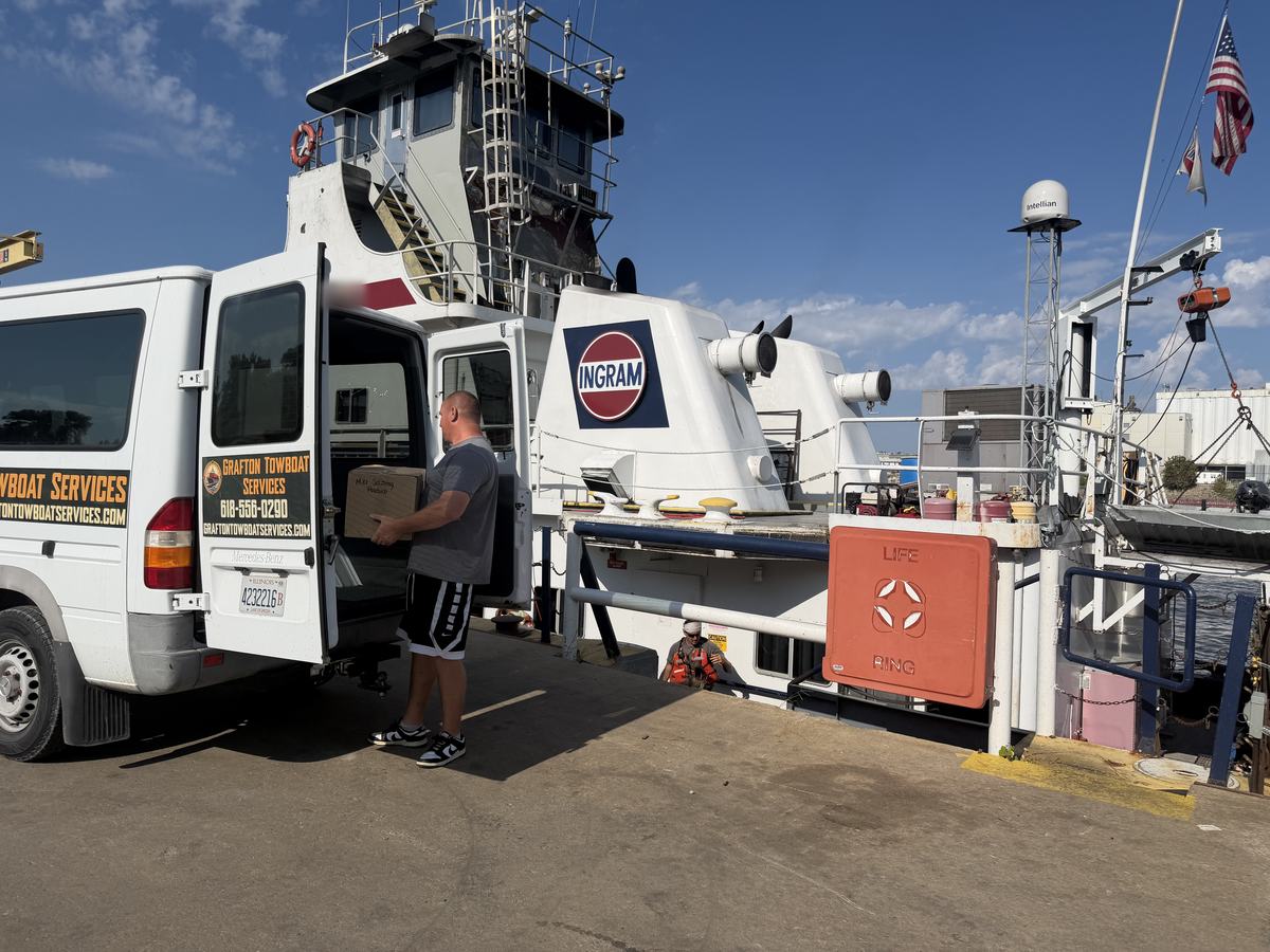 Grafton Towboat Services staff loading supplies from the van onto a towboat at the dock