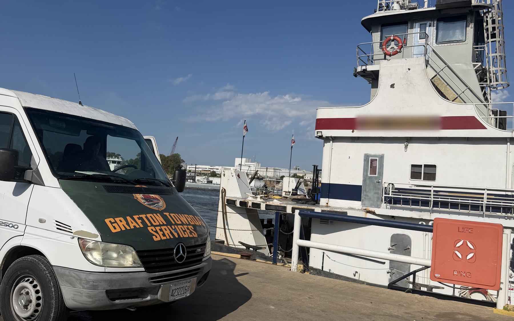 The Grafton Towboat Services van parked alongside a towboat at the dock, delivering supplies